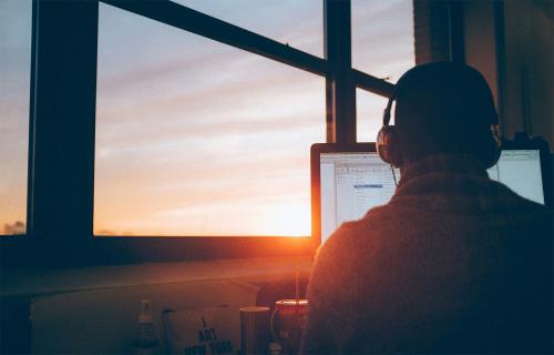 A person using a computer during sunset.