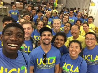 Group of smiling people in matching blue shirts at an indoor event.