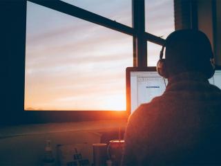 A person using a computer during sunset.